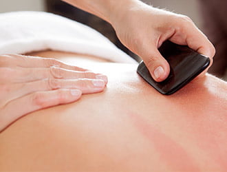 Gua Sha treatment using traditional scraping tools on the skin